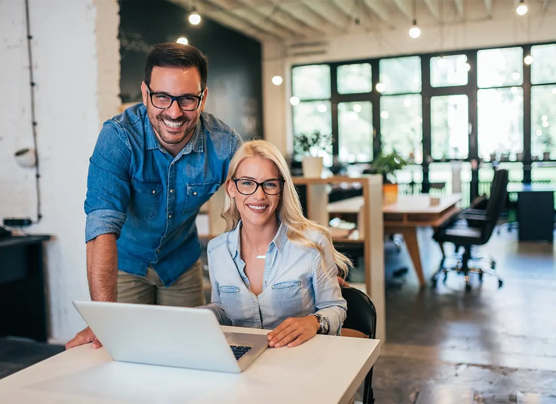 Two smiling business owners at a laptop in a bright office